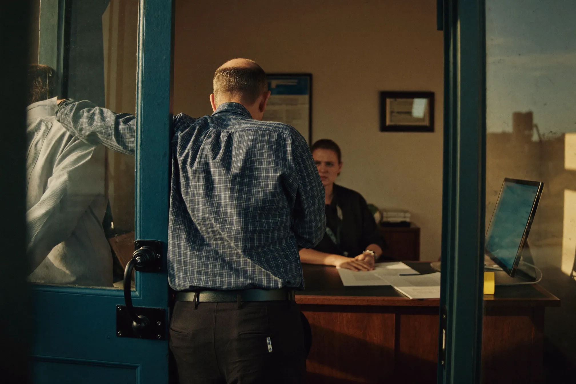A supervisor pauses in the doorway of a small-business owner's office